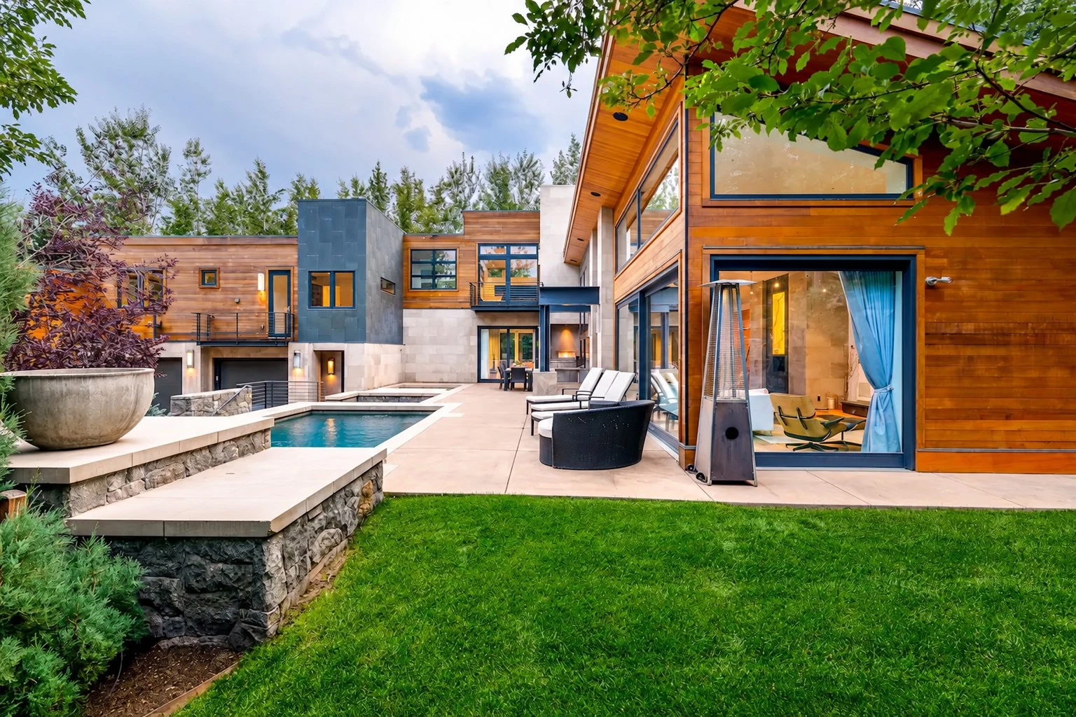 Contemporary wood-and-stone home overlooking a landscaped pool terrace